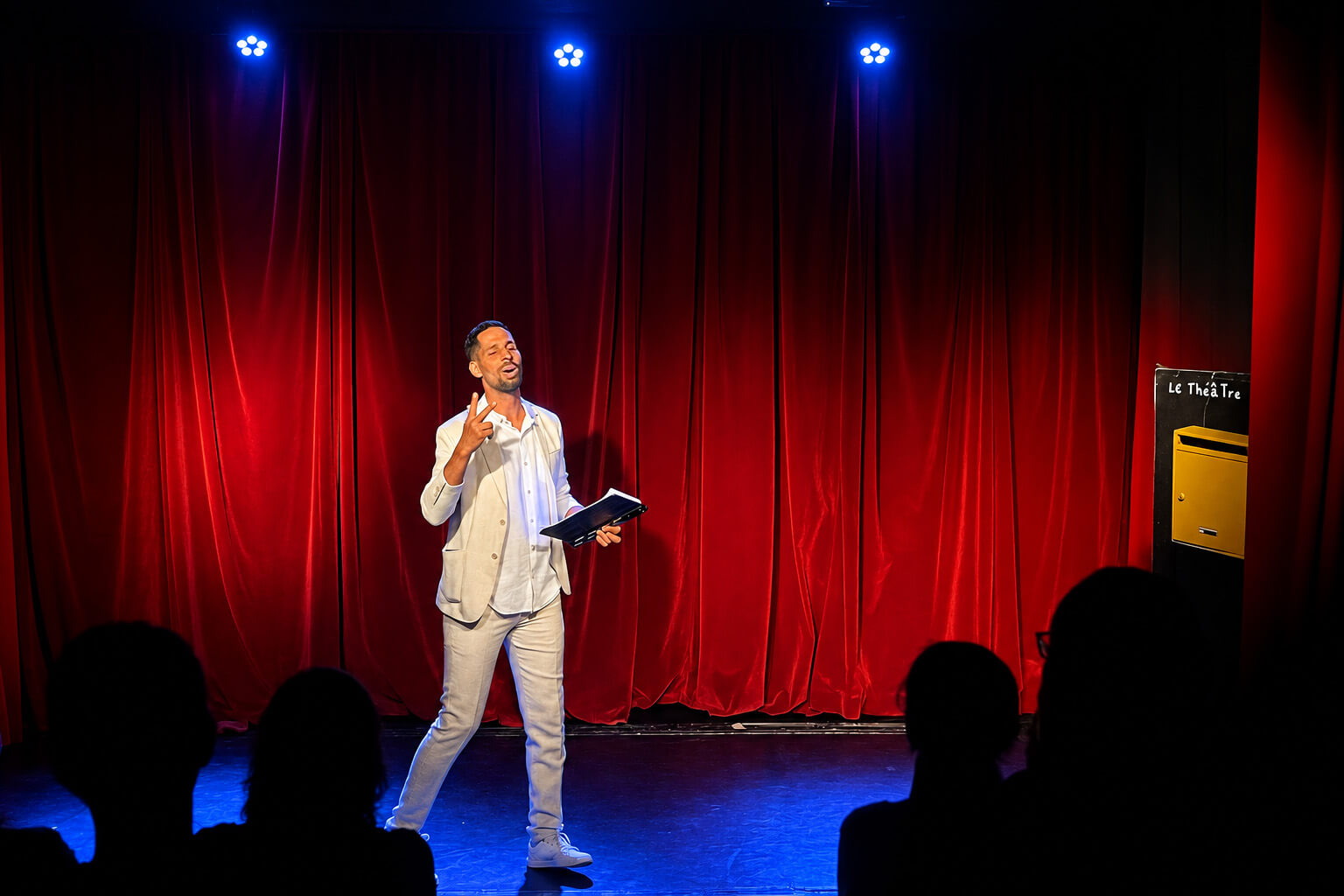 Impro Shuffle Show — photo dans la bulle Le présentateur de l’Impro Shuffle Show devant les rideaux rouges du théâtre.